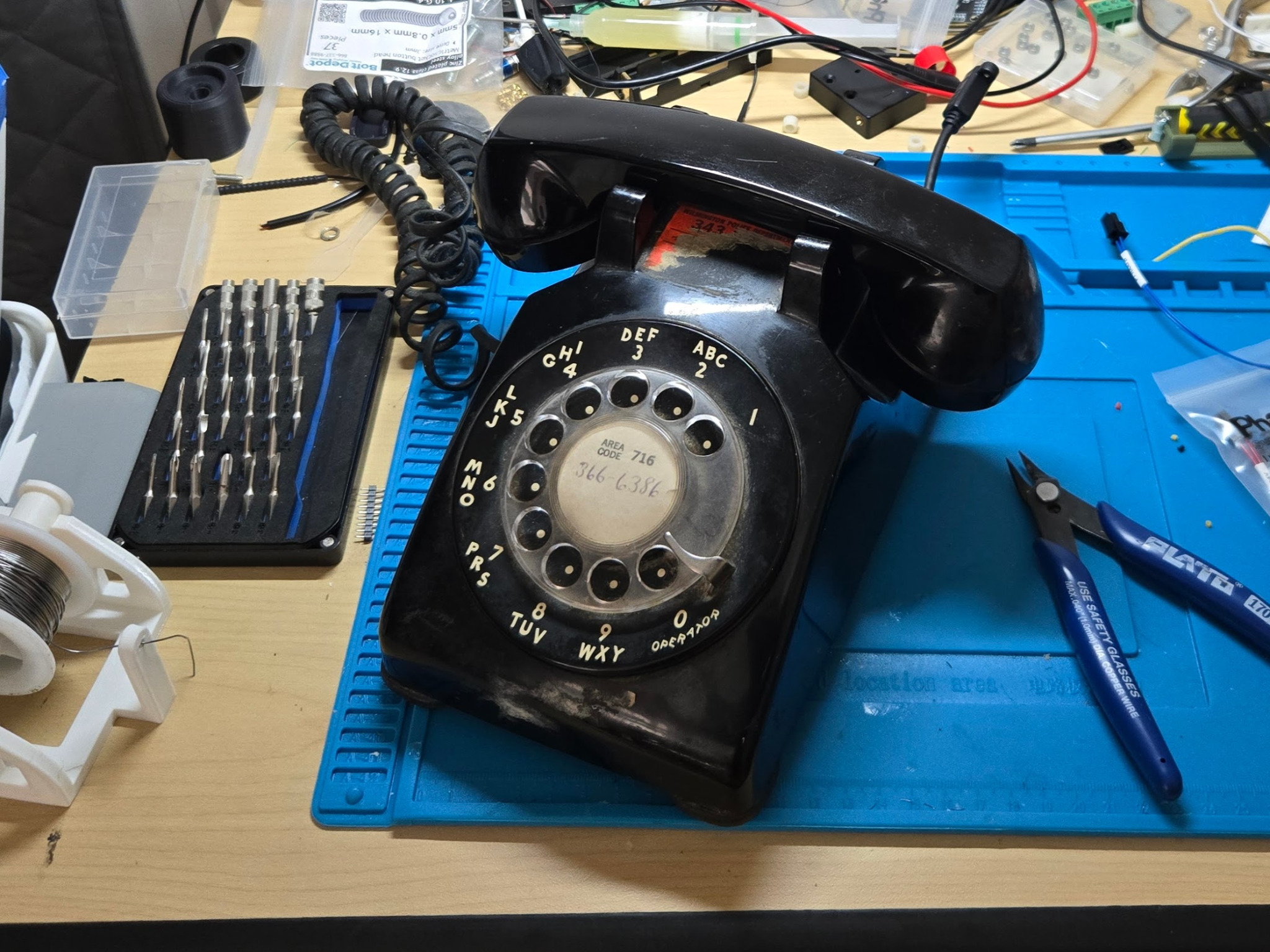 Black rotary telephone on an electronics workbench