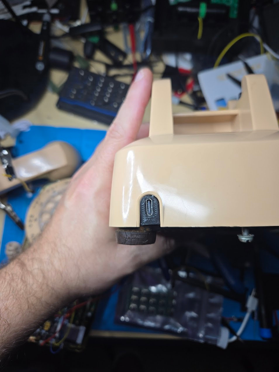 Arch R1 USB-C charging insert fitted to the captive-cord opening of a beige telephone